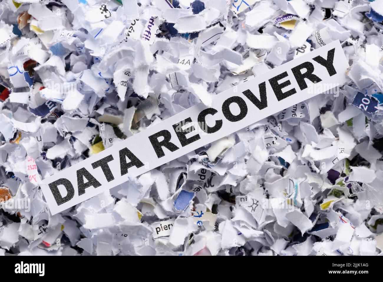 Words Data recovery on top of heap of cross shredded paper concept top view Stock Photo