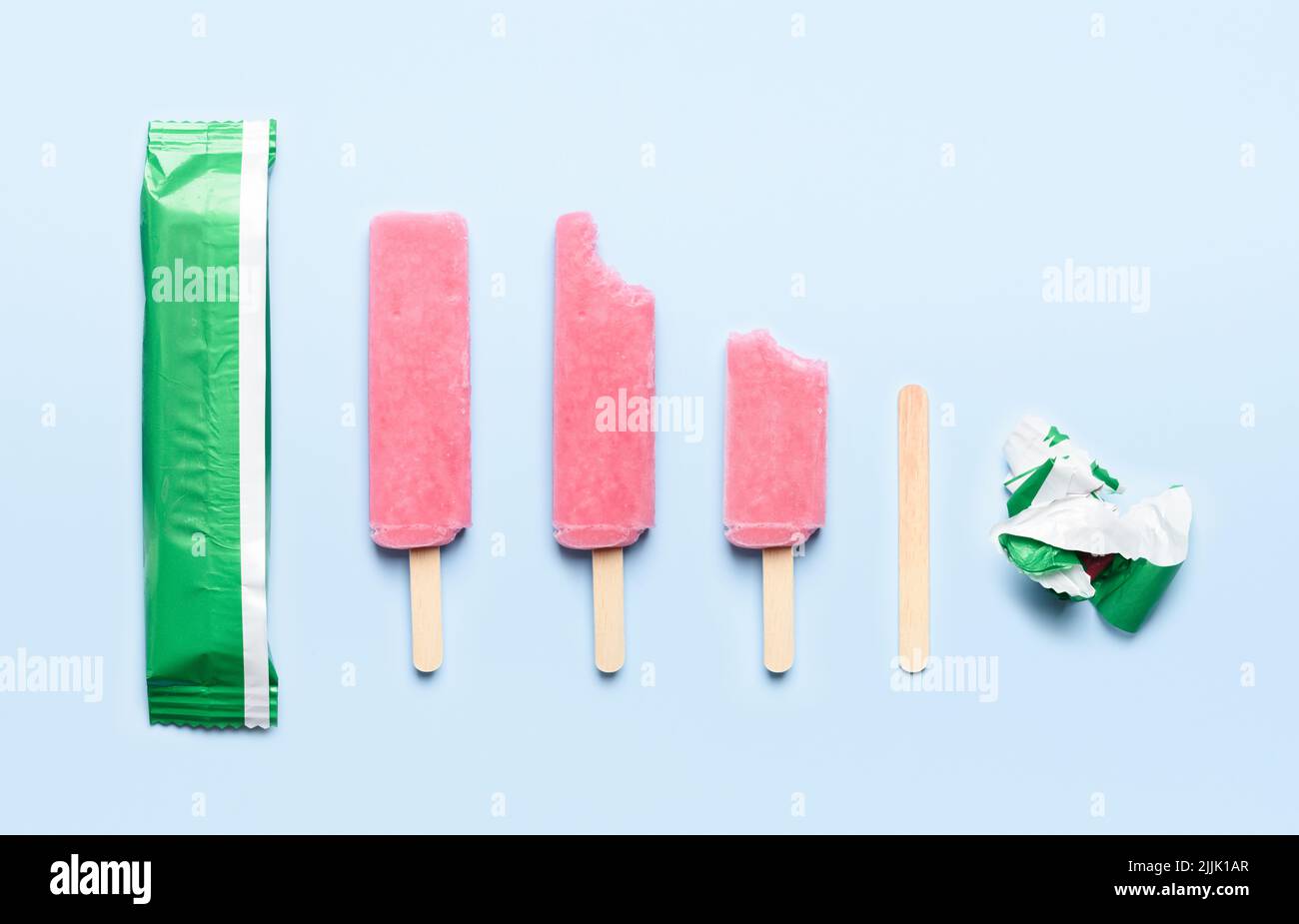 Pink popsicle ice cream on wooden stick at different states of consumption life cycle on blue background top view flat lay Stock Photo