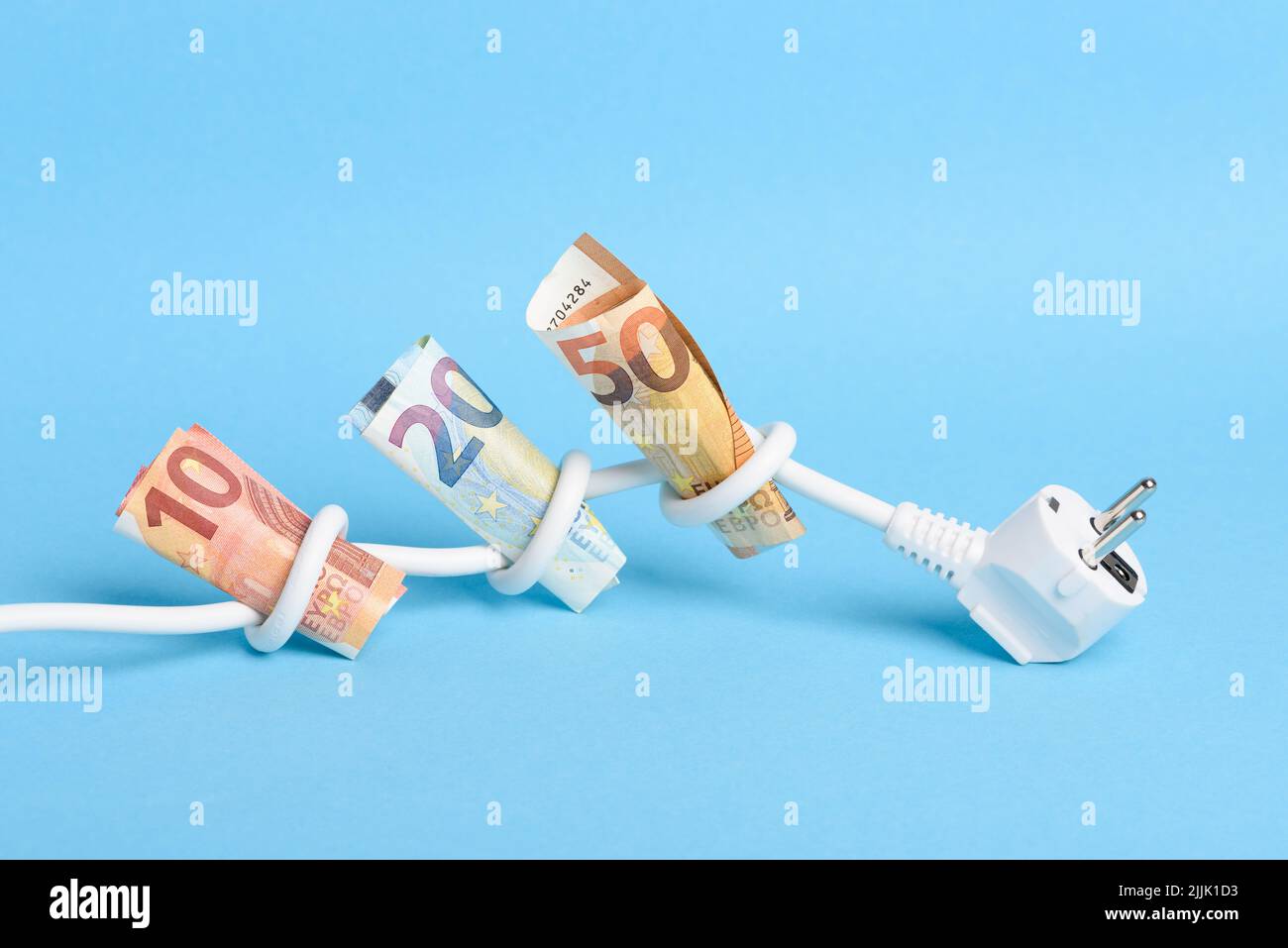 Euro bills tied in knots in power electrical power cable on blue background. Concept of expensive electricity costs in Europe and rise in energy bill Stock Photo