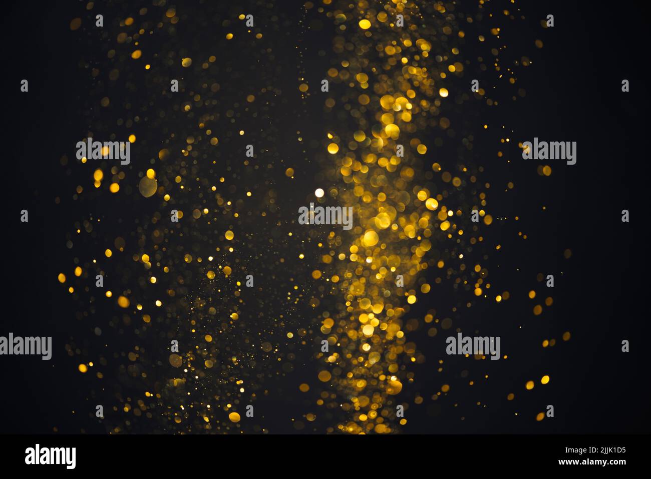Glowing golden glitter shiny particles lights abstract bokeh dark background Stock Photo