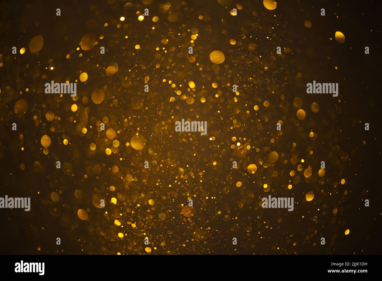 Glowing golden glitter festive lights abstract bokeh dark background Stock Photo