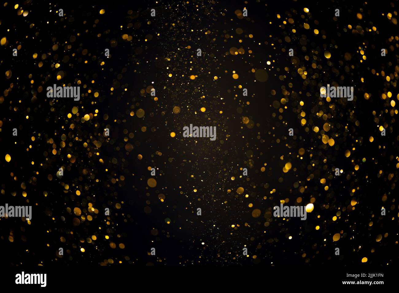 Swirly bokeh of gold glitter shimmer dust shiny particles dark abstract background Stock Photo