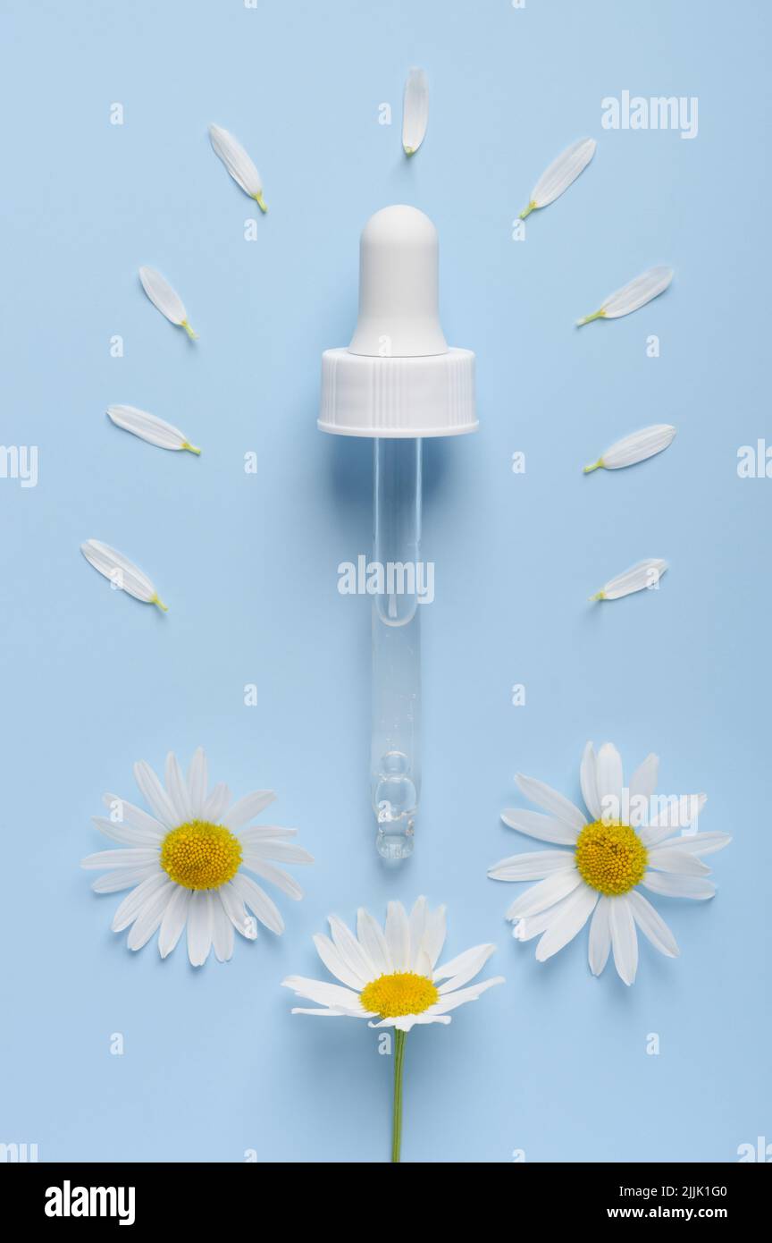 Cosmetic skincare serum dropper with chamomile flowers and petals on