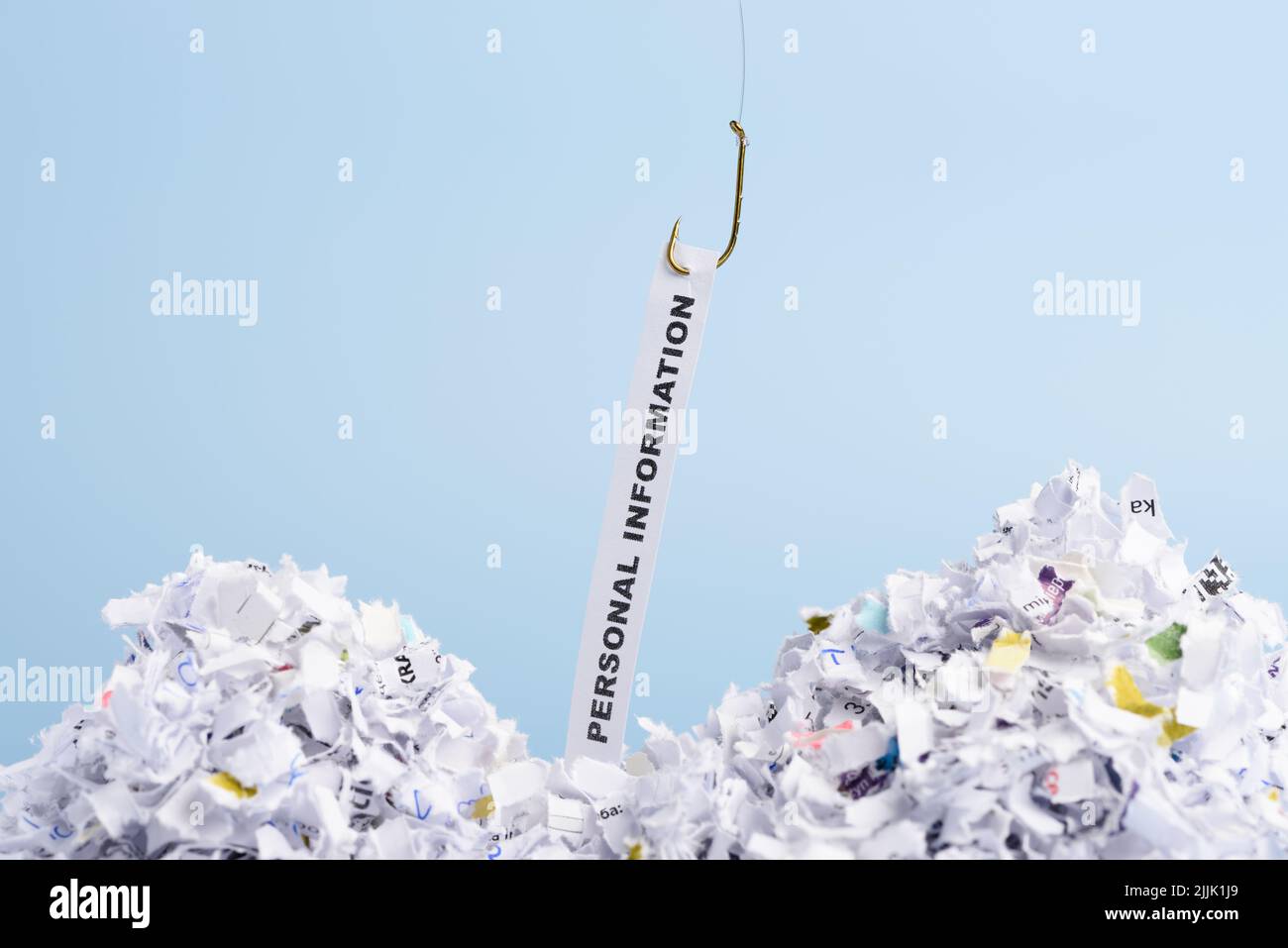 Words Personal information hooked on fishing hook pulled from pile of shredded documents on blue background. User data stealing concept. Stock Photo