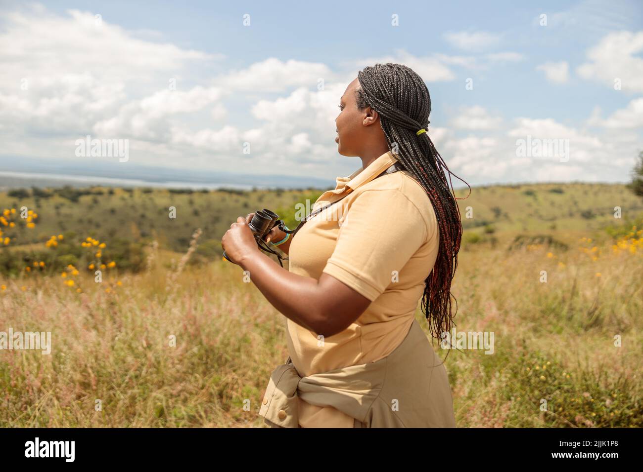 Professional female guide searching the landscape for wildlife in the savannah Stock Photo