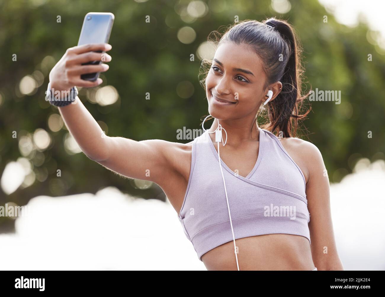 Getting my body in the best shape. a sporty young woman wearing earphones and taking selfies while exercising outdoors Stock Photo Alamy