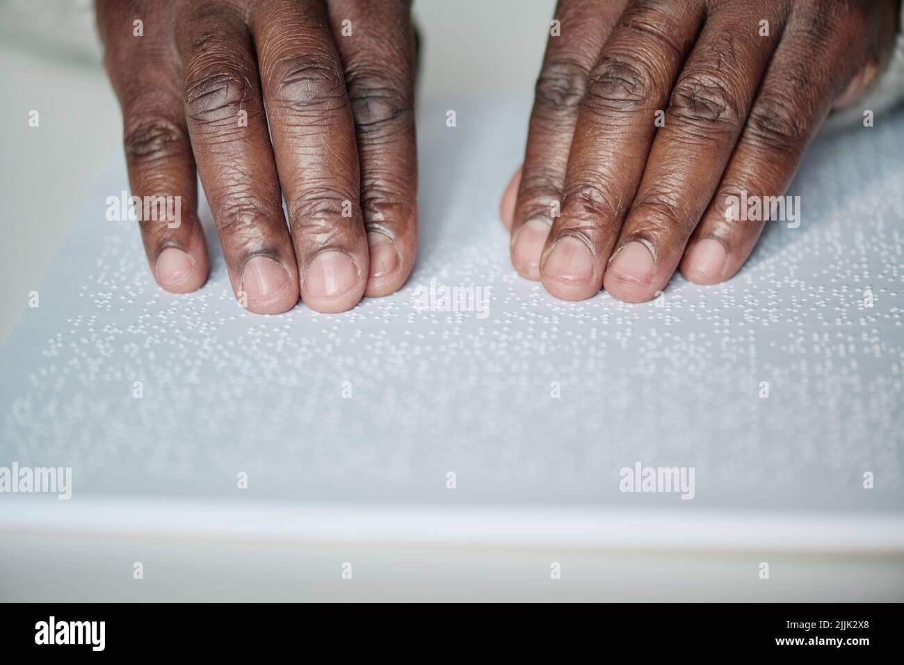 Close-up of senior blind man reading book with braille language at table Stock Photo
