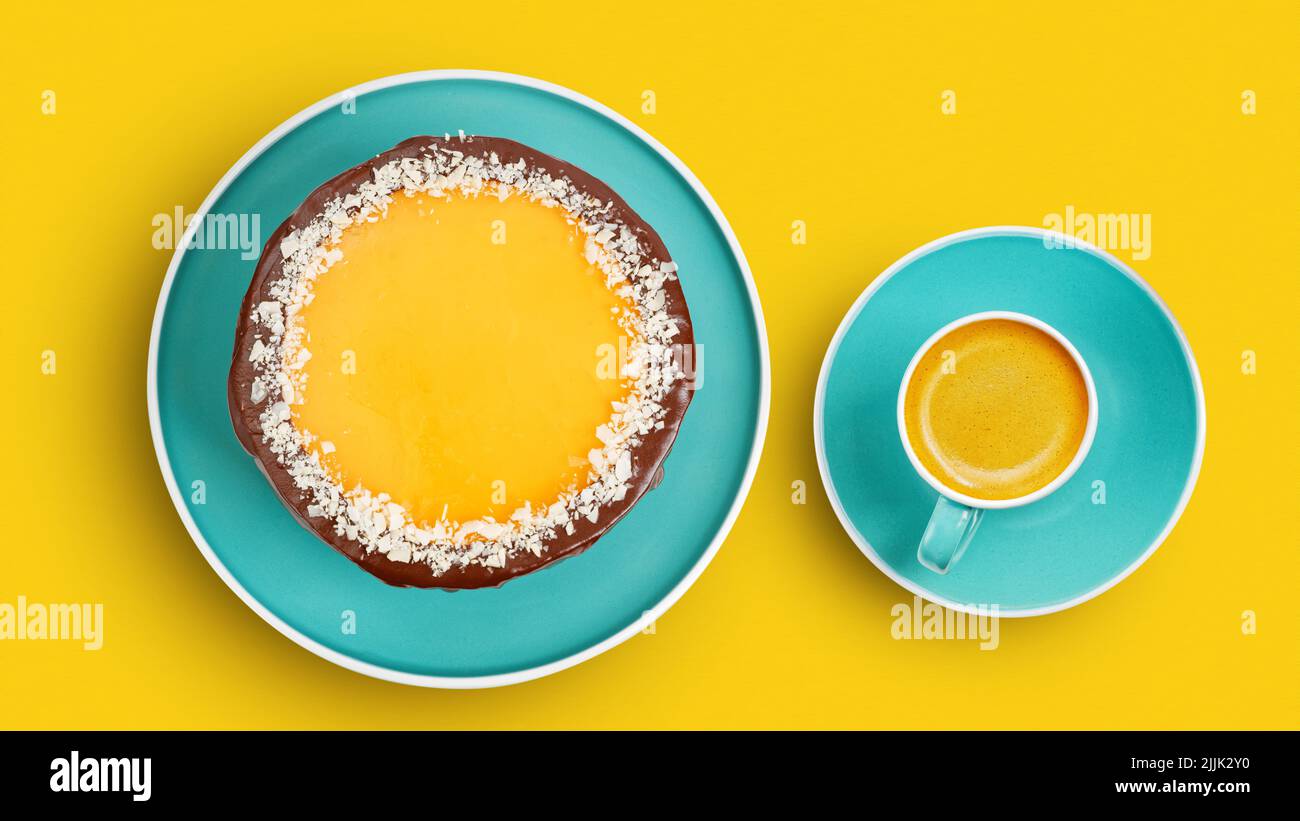 Homemade chocolate and orange cheesecake sprinkled with almond slices and cup of coffee on orange background. Top view. Stock Photo