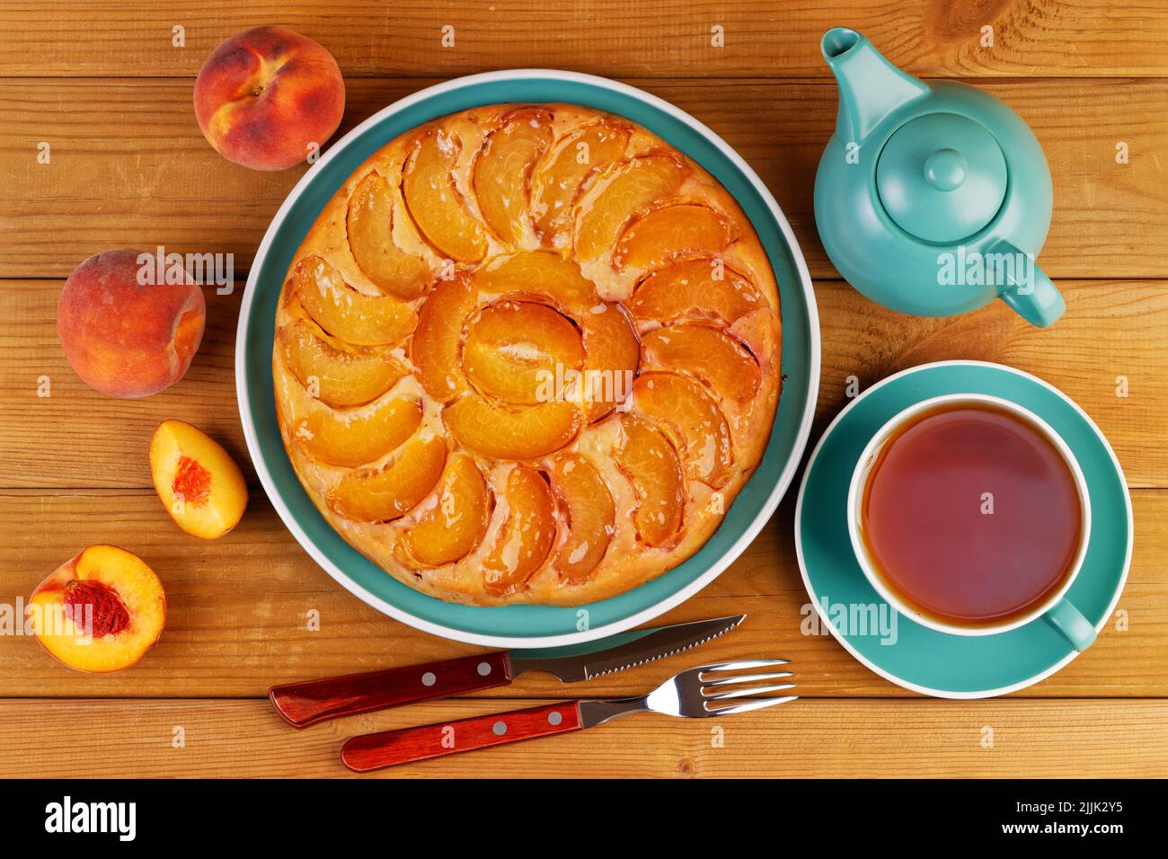 Homemade pie with peaches and cup of tea on wooden table. Top view. Stock Photo