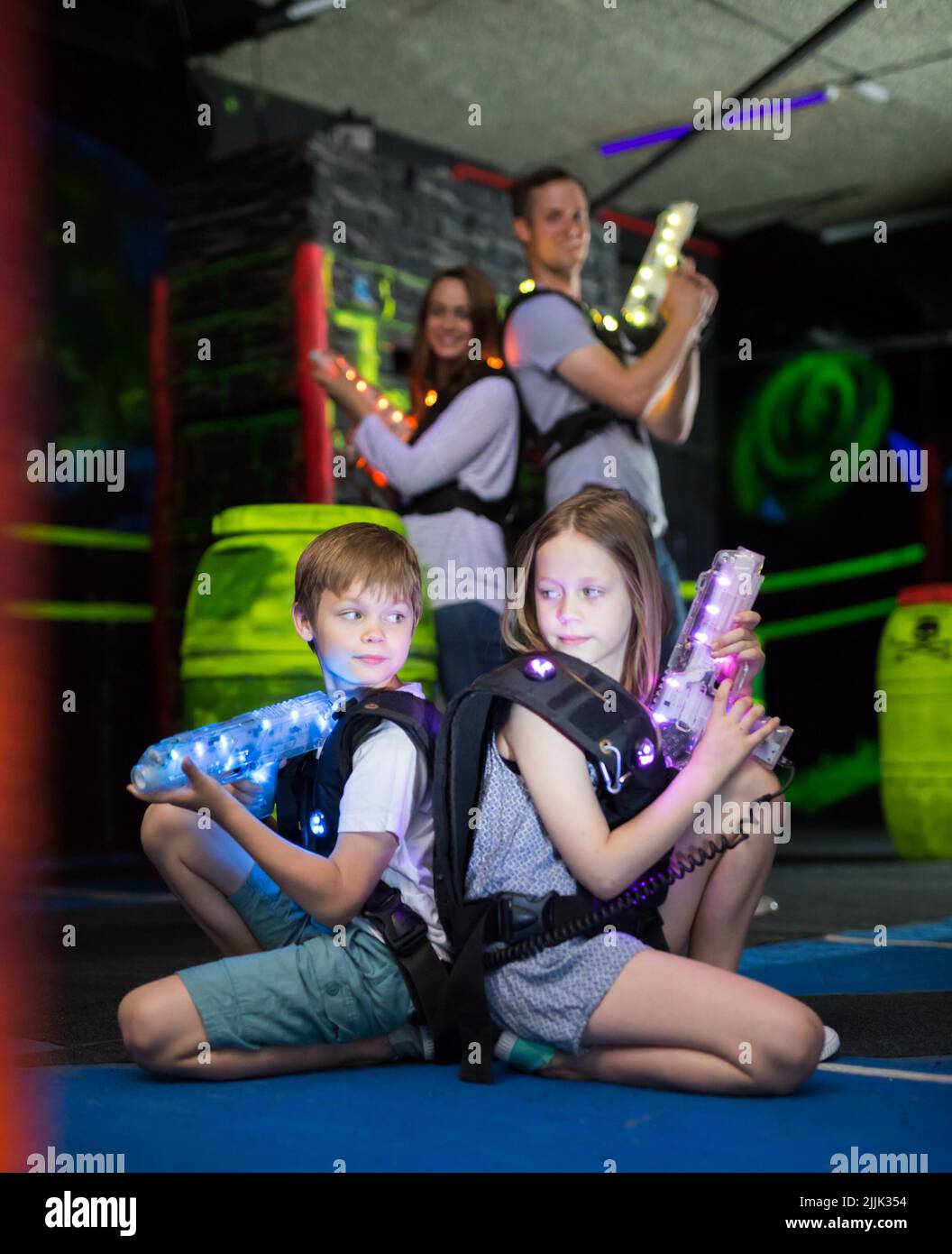 Kids sitting back to back with laser guns Stock Photo