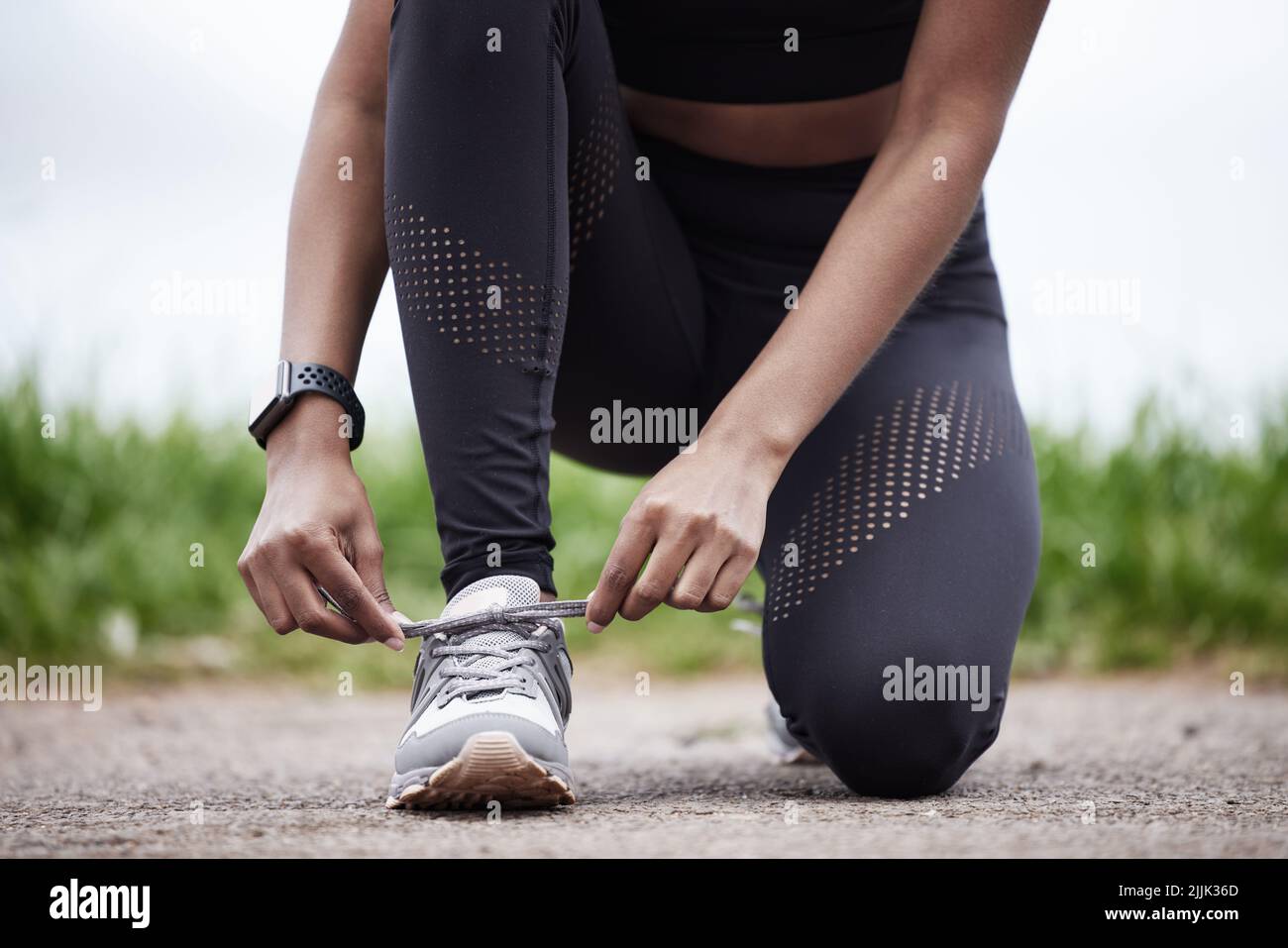 Ready to give it her all. Closeup shot of an unrecognisable woman tying her shoelaces while exercising outdoors. Stock Photo