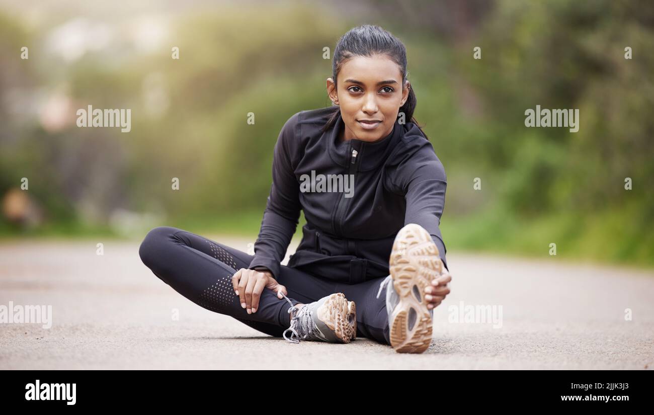 My journey will be amazing. a sporty young woman stretching her legs while exercising outdoors. Stock Photo