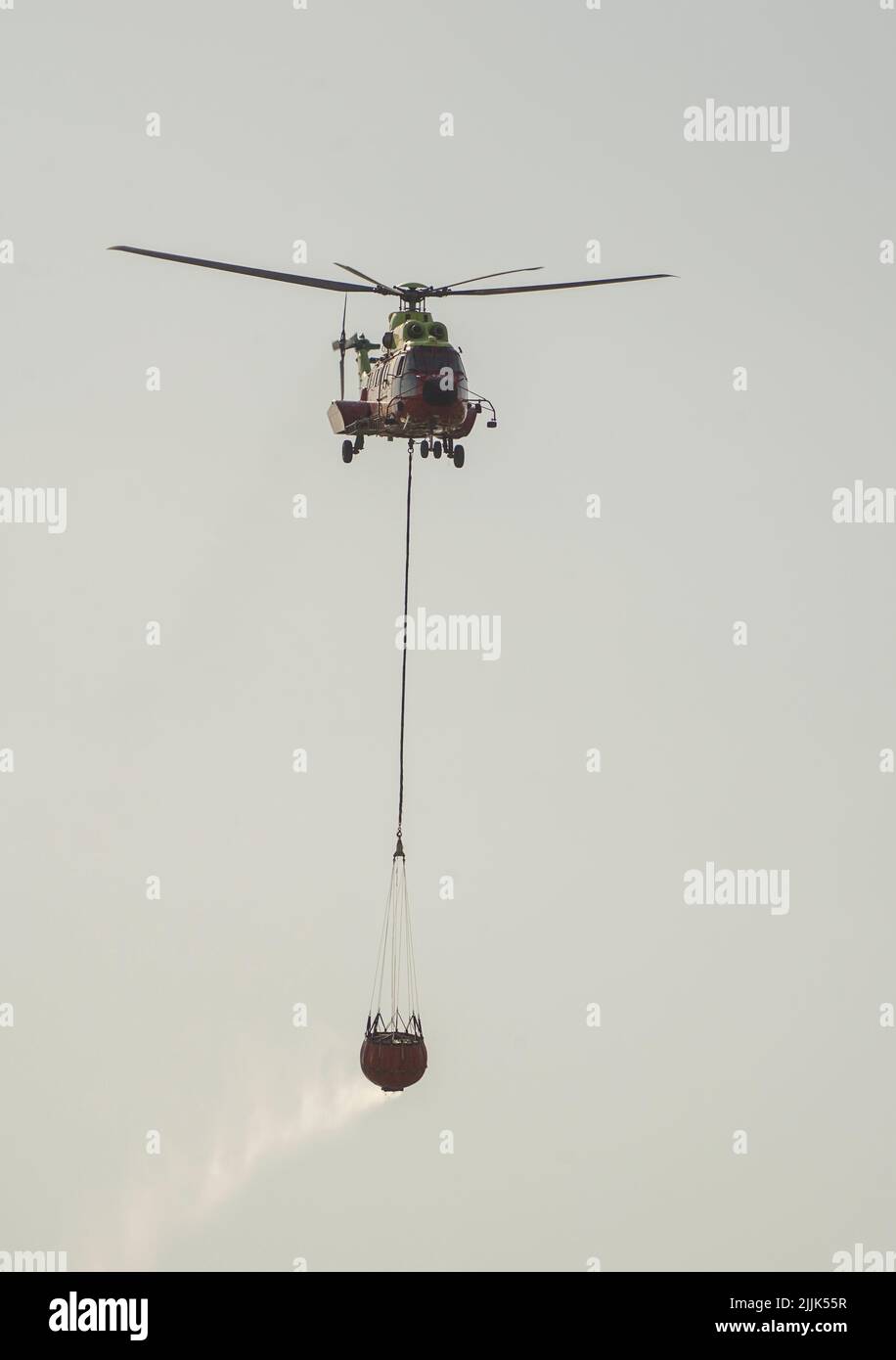 Helicopter of INFOCA carrying a water bucket to drop on a wildfire, Mijas, Spain Stock Photo Alamy