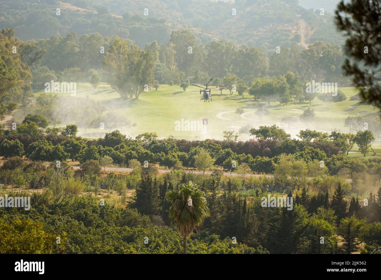 Helicopter of INFOCA scooping up water from a artificial pond on a golf course, to drop on a wildfire, Mijas, Spain. Stock Photo