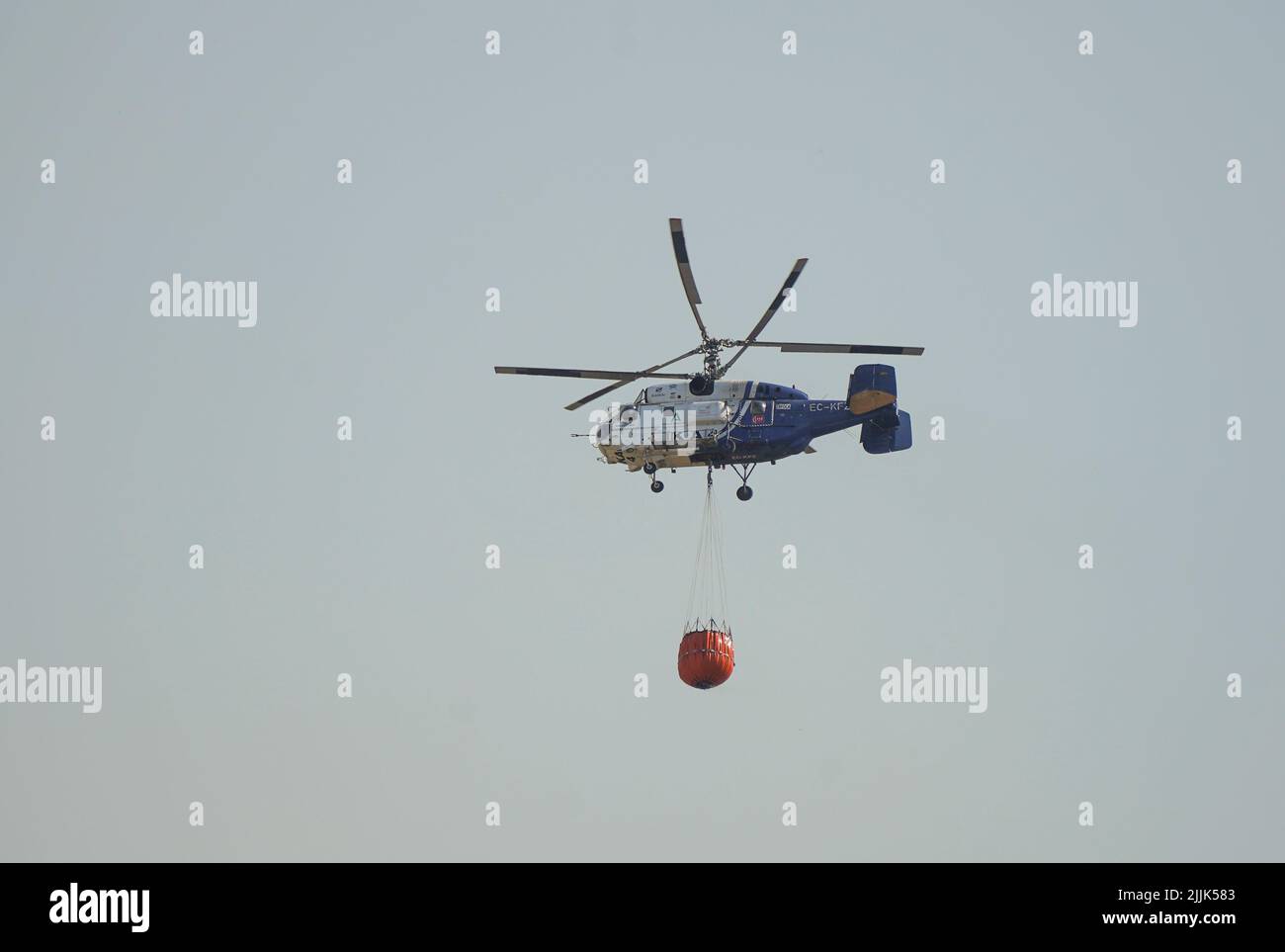 Heavy helicopter of INFOCA carrying a water bucket to drop on a wildfire, Mijas, Spain. Stock Photo