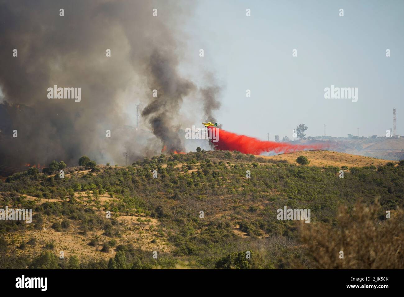 Plane dropping red flame retardant on wildfire in Mijas, Andalucia, Spain. Stock Photo