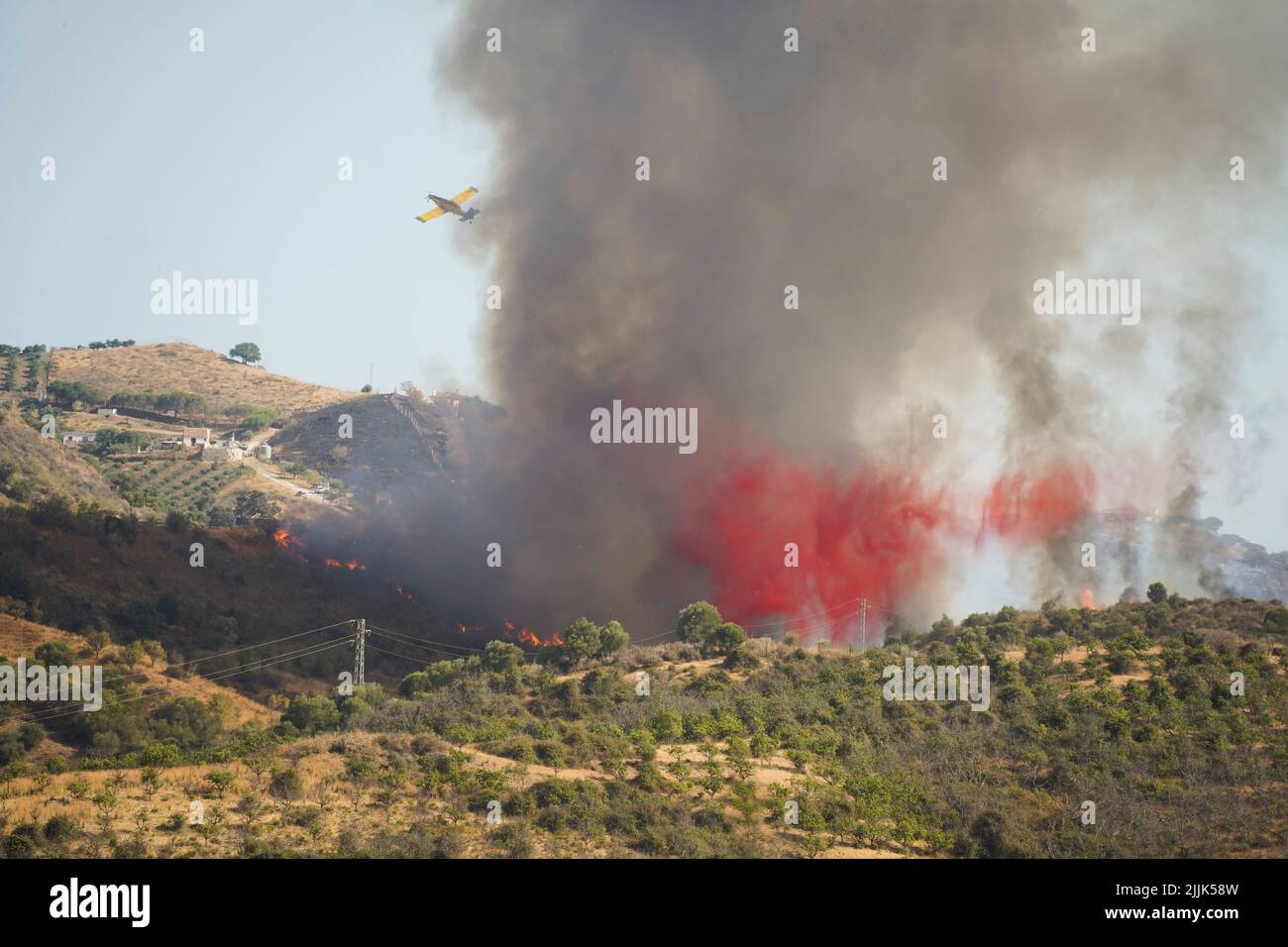 Plane dropping red flame retardant on wildfire in Mijas, Andalucia, Spain. Stock Photo