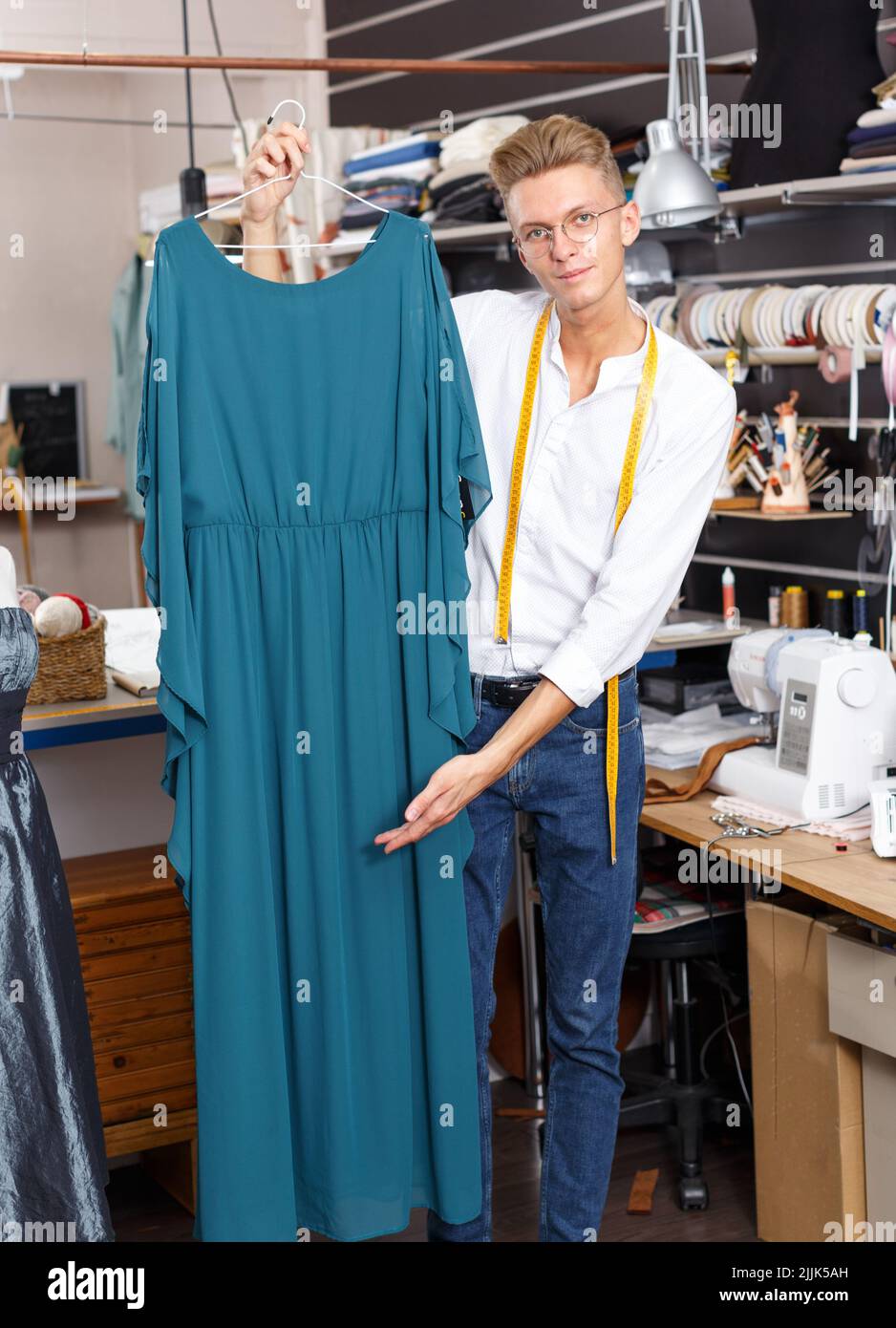 Tailor showing dress on hanger Stock Photo - Alamy