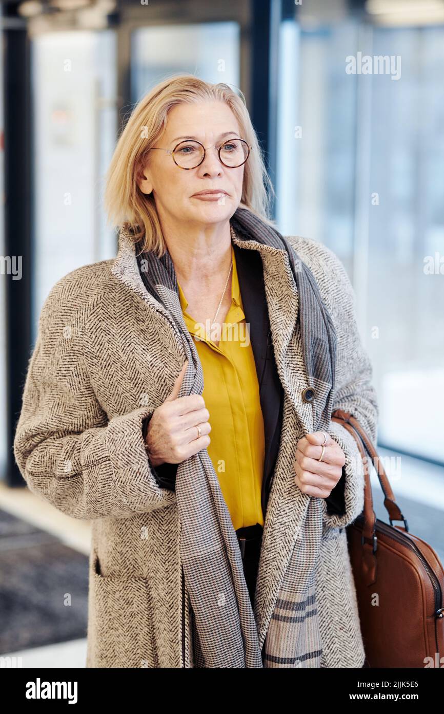 Professional mature female lawyer in the warm coat entering in the courthouse, she looking very seriously Stock Photo