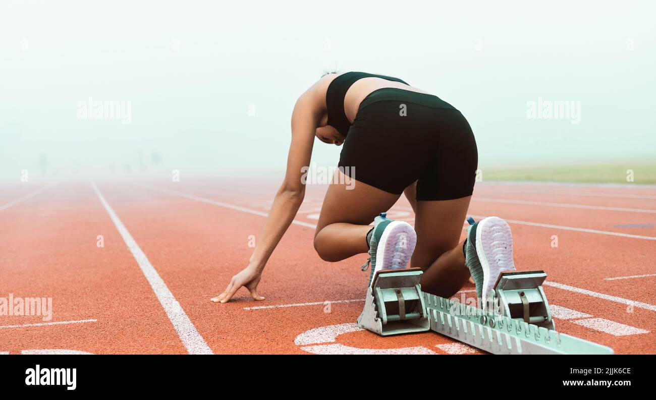 Shes race ready. Rearview shot of an unrecognizable young sportswoman taking her mark on starting blocks. Stock Photo