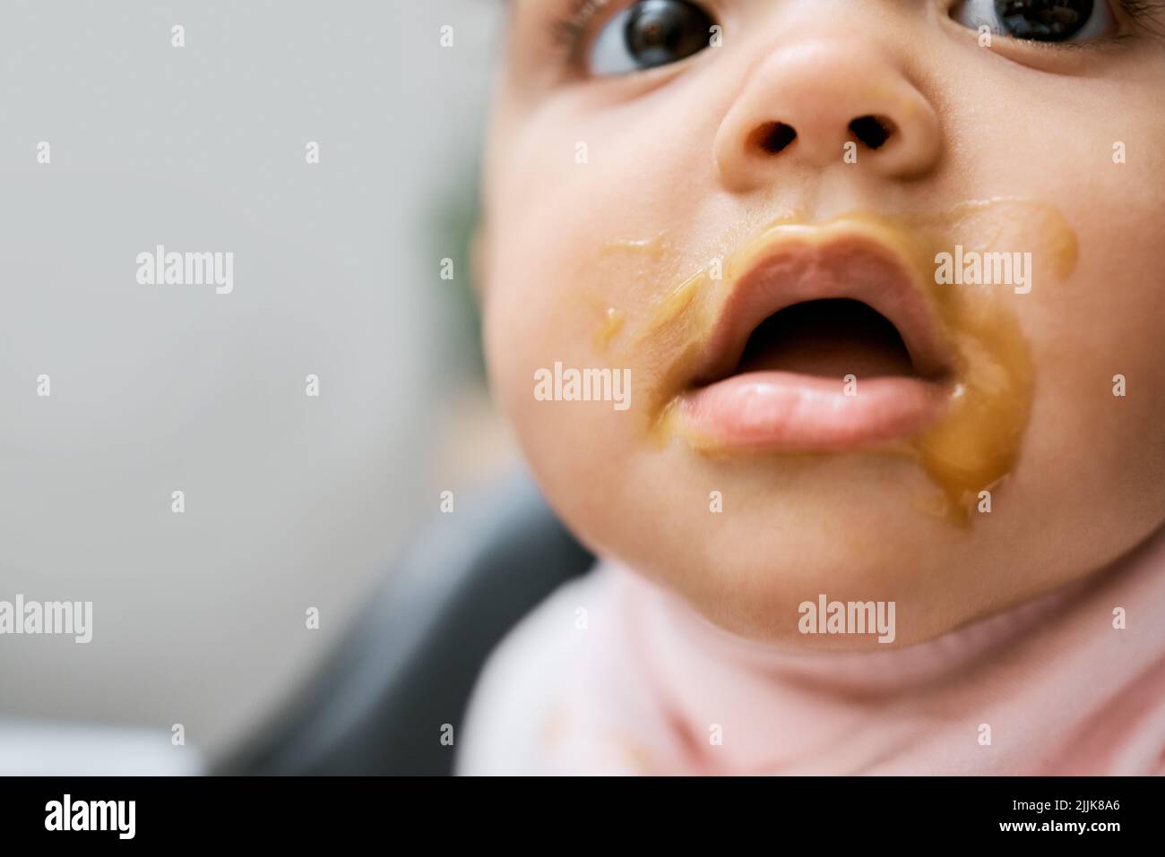 Gimme some more of that. an adorable baby girls mouth covered with baby food. Stock Photo