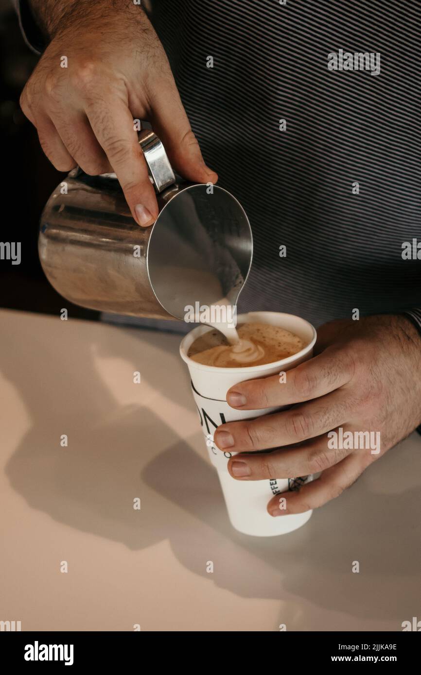 The barista's hands add milk for making a cappuccino Stock Photo Alamy