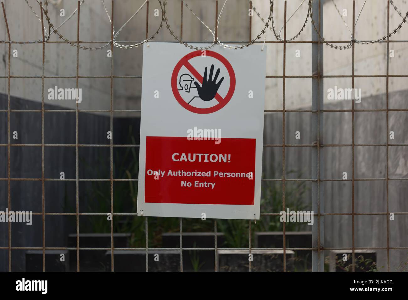 Prohibition Sign and razor wire. 'Caution authorized personnel only. No entry.' text and stop gesture sketch. Stock Photo