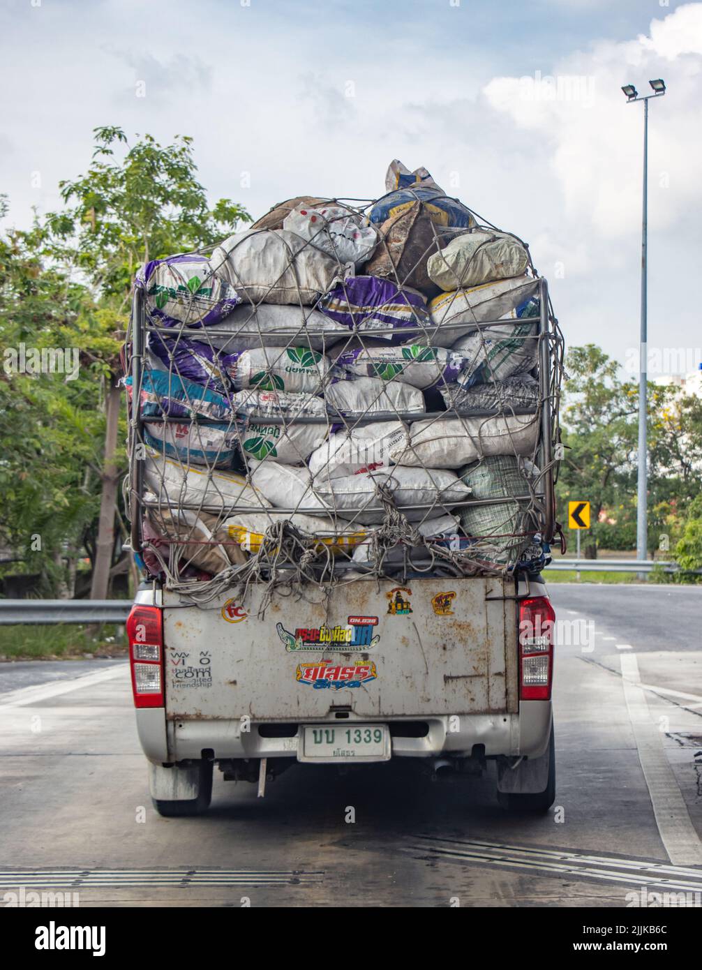 SAMUT PRAKAN, THAILAND, MAY 12 2022, A pickup truck is driving down the road, fully loaded with sacks Stock Photo