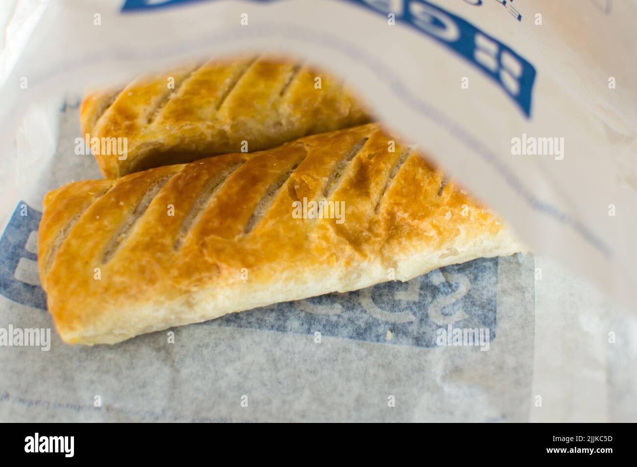 Greggs Sausage roll inside a Greggs printed paper bag Stock Photo