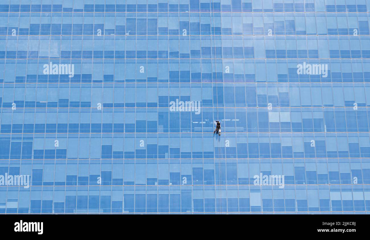 A window cleaner with safety harness cleaning glass windows of a modern
