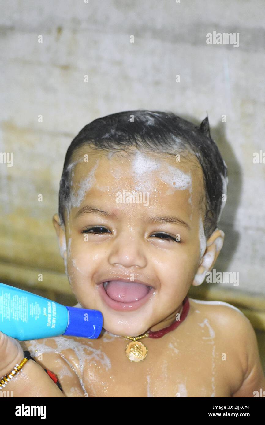 A vertical portrait of a cheerful little baby boy with foam on his body
