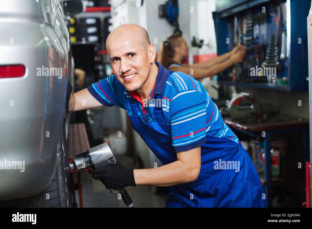 Mature male technician fitting new car tyre Stock Photo