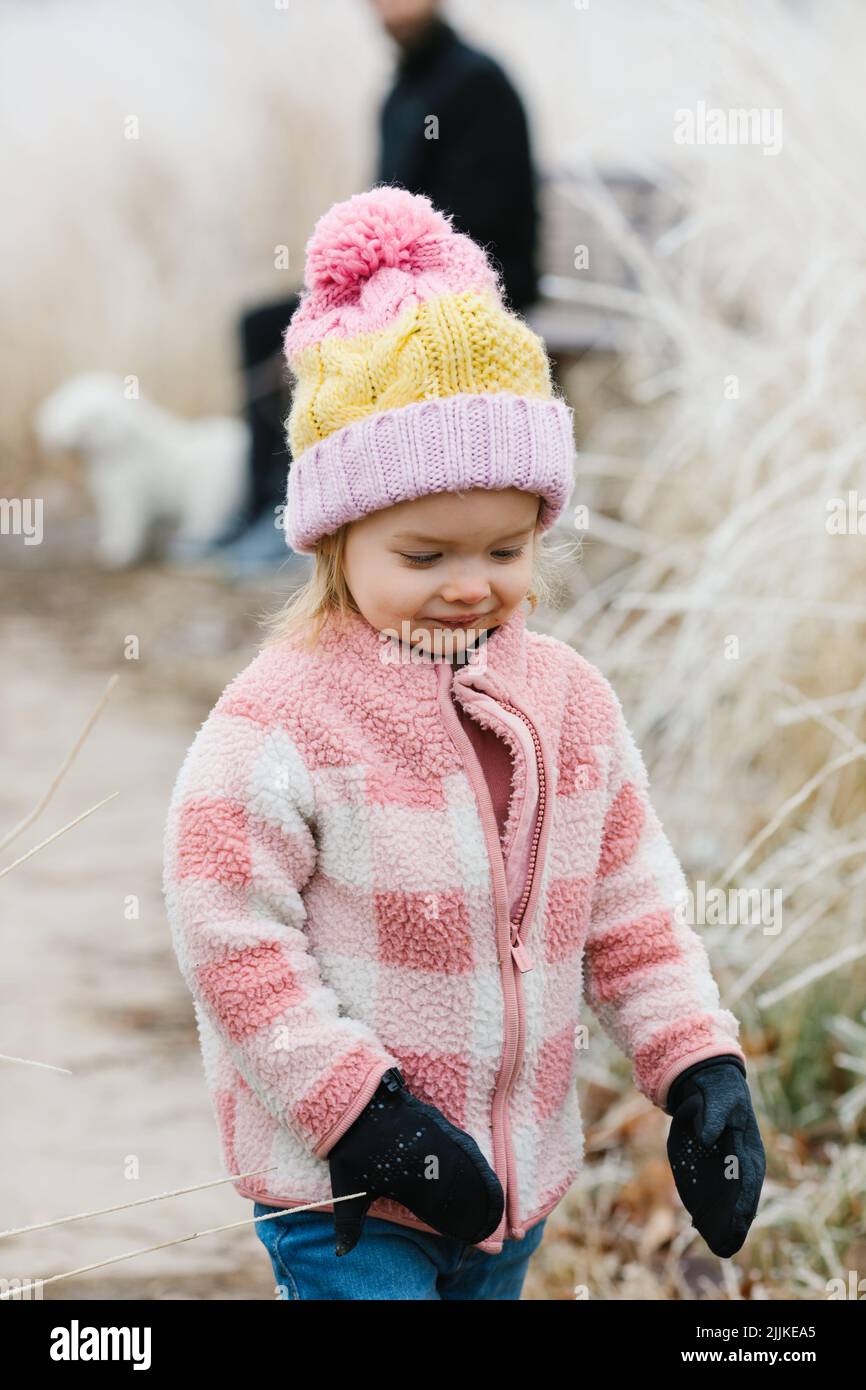 A closeup portrait of a little girl wearing a pink jacket walking on a ...