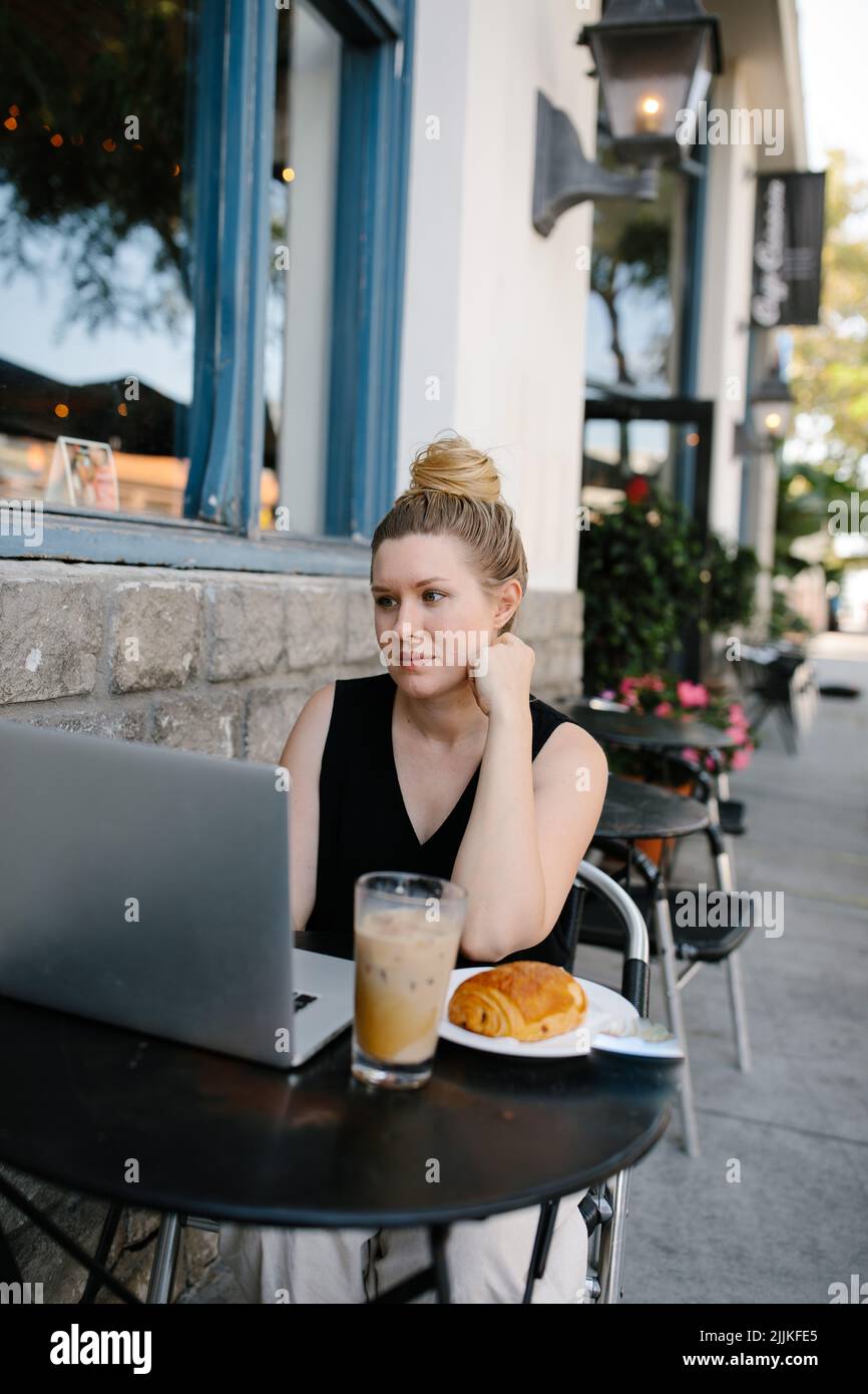 A beautiful Caucasian businesswoman working remotely from an outdoor coffee shop Stock Photo