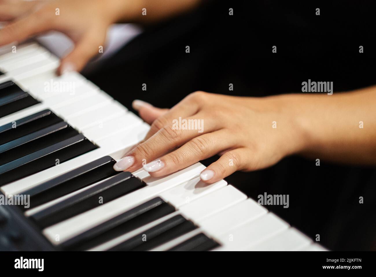 A closeup shot of the female hands playing a piano Stock Photo