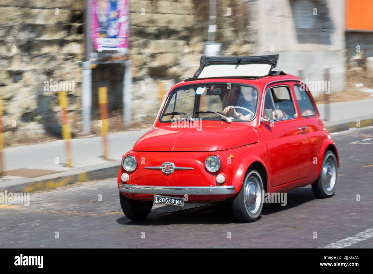A fiat 500 race car from the 1970s driving down the street Stock Photo