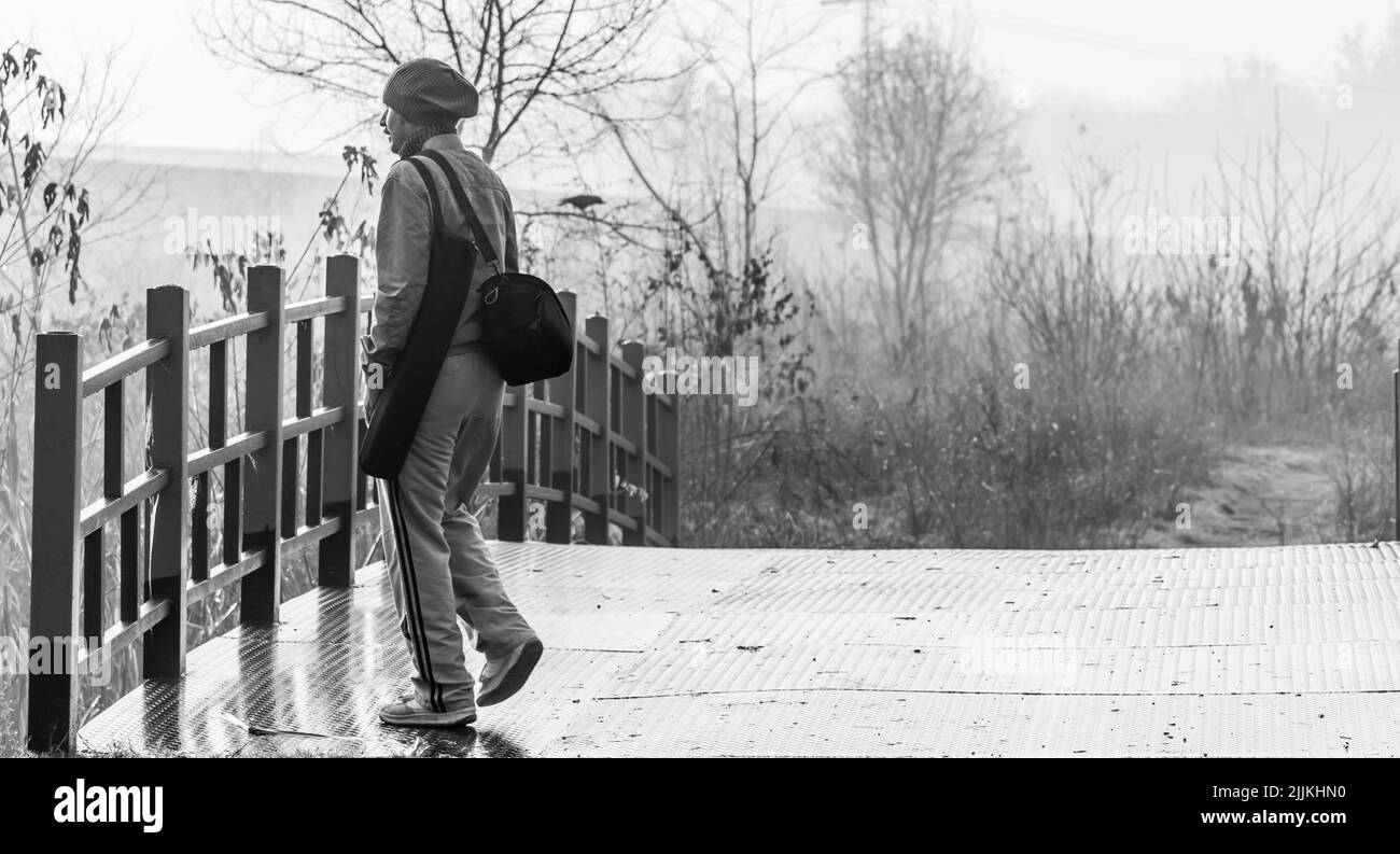 A grayscale of a tourist enjoying the view from the bridge Stock Photo