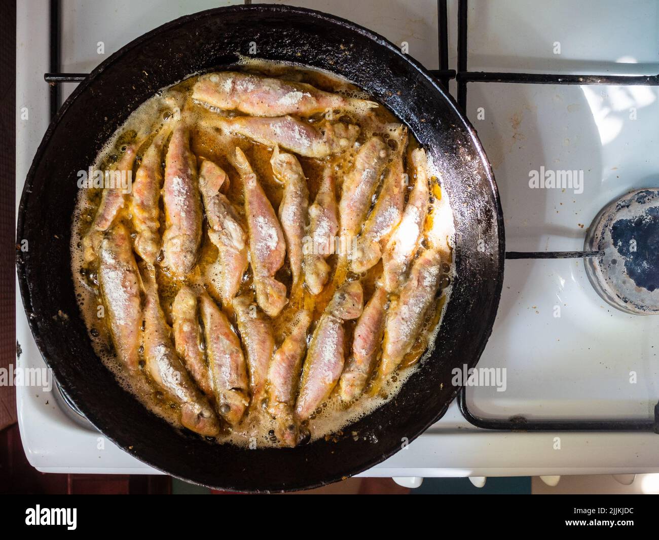 top view of frying breaded Black Sea surmullet fishes in old round cast