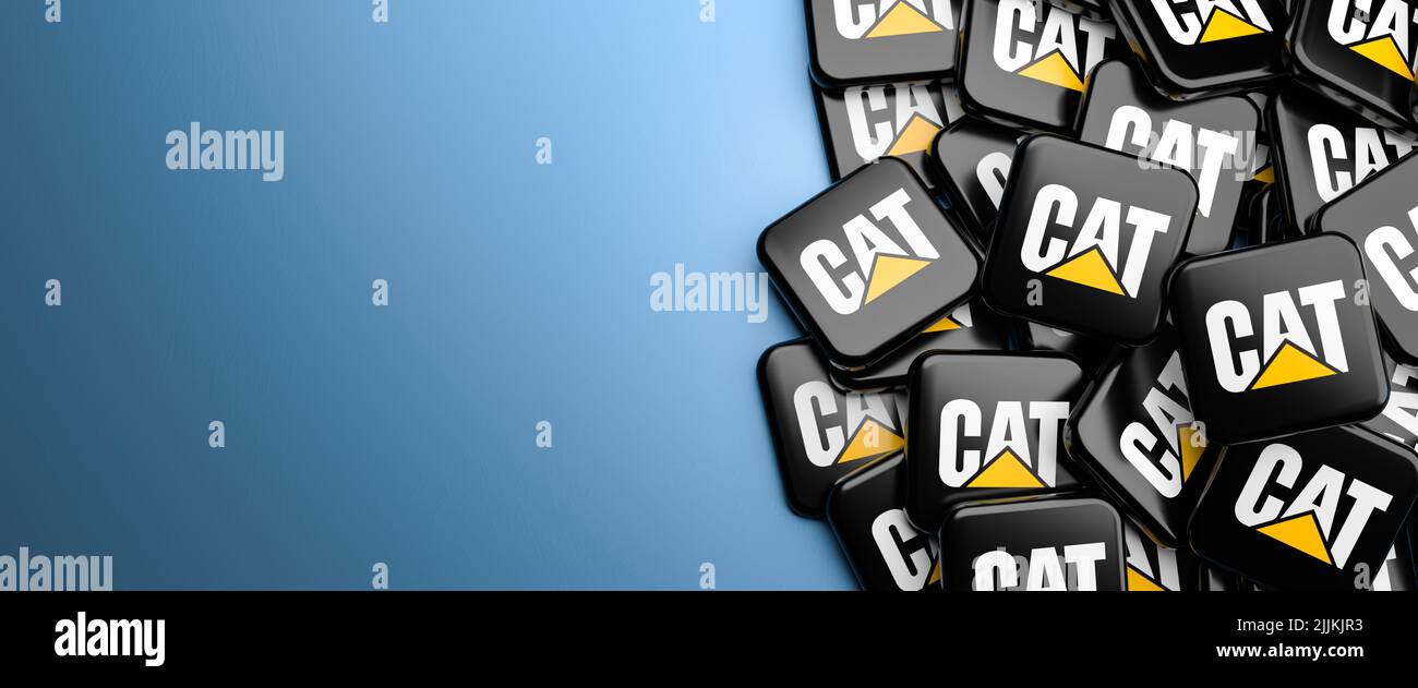 Logos of the construction equipment manufacturer Caterpillar on a heap on a table. Copy space. Web banner format. Stock Photo