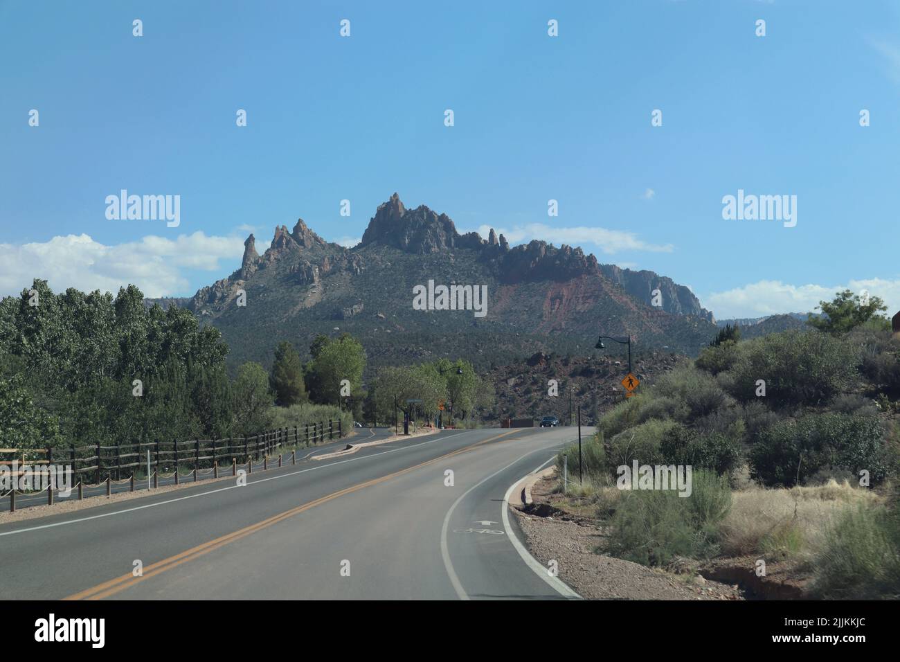 A natural view of a curved asphalt road with a high mountain and a ...