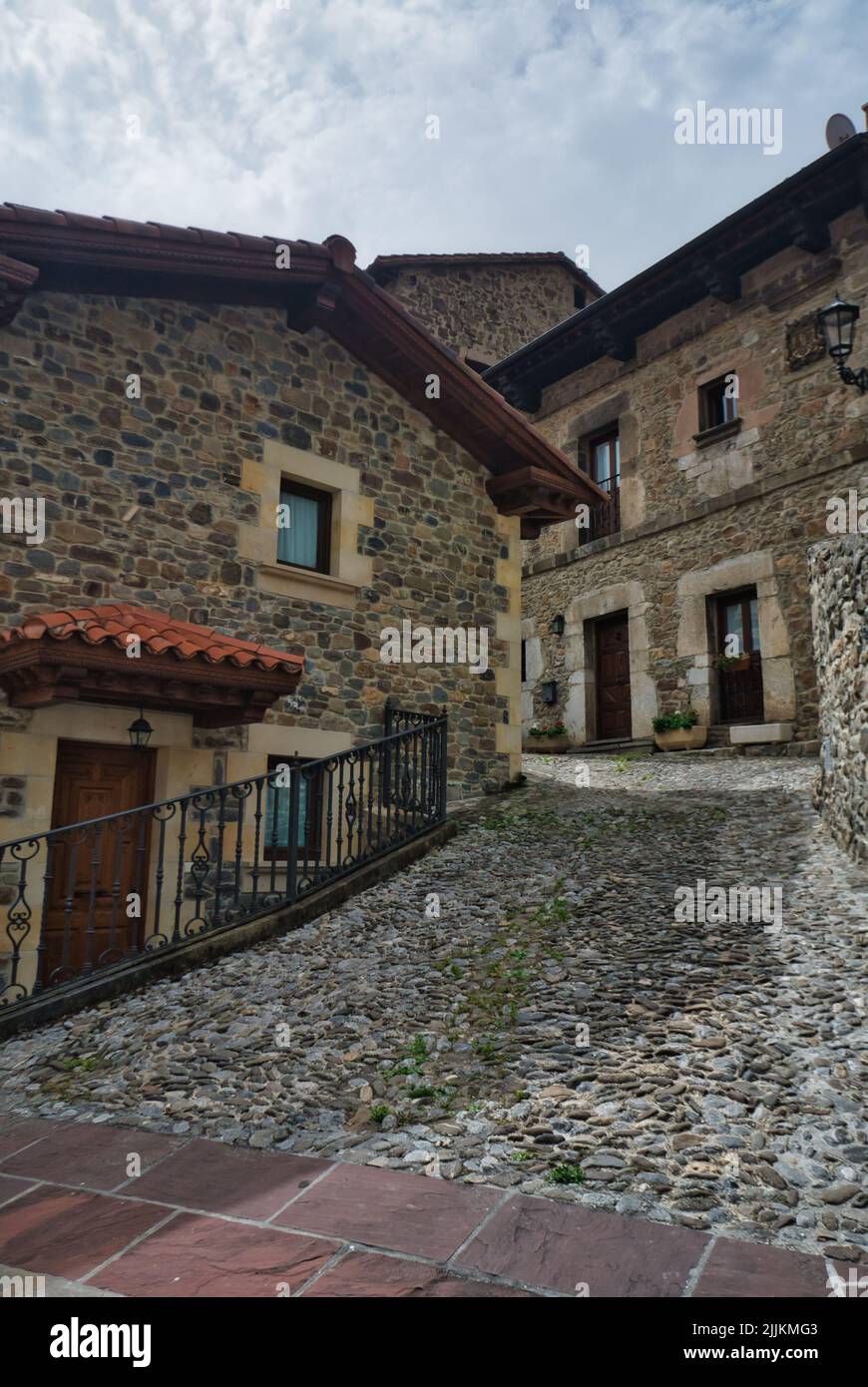 A vertical shot of a cobblestone alley near stone houses in Potes, Spain Stock Photo
