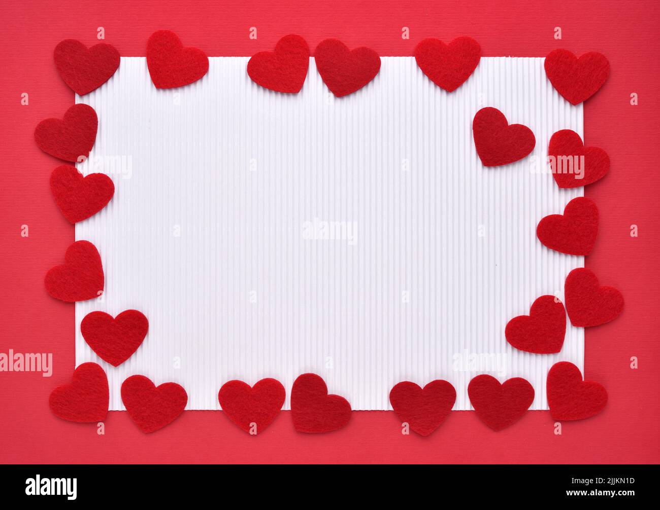 Felt hearts on red and white paper. Valentine's Day concept. Top view with copy space for text. Stock Photo