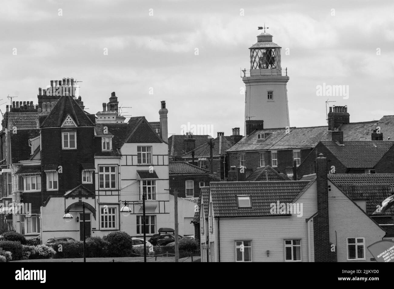 A black and white shot of apartment buildings with a tall lighthouse in the background Stock Photo