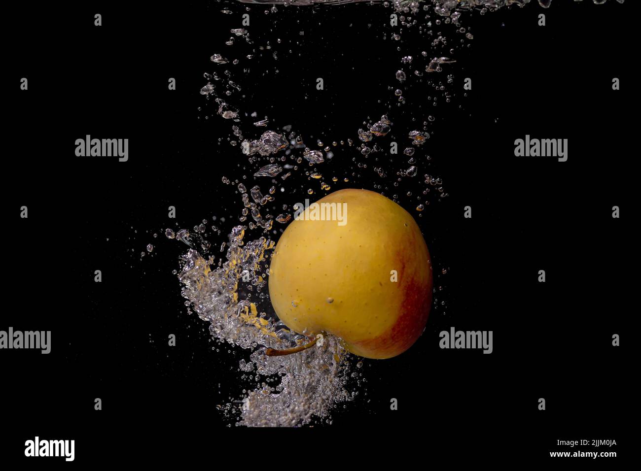 An apple with water splashes on a black background Stock Photo