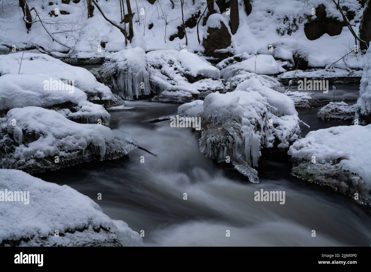 A photo of a flowing river and rocks covered in frost and snow Stock ...