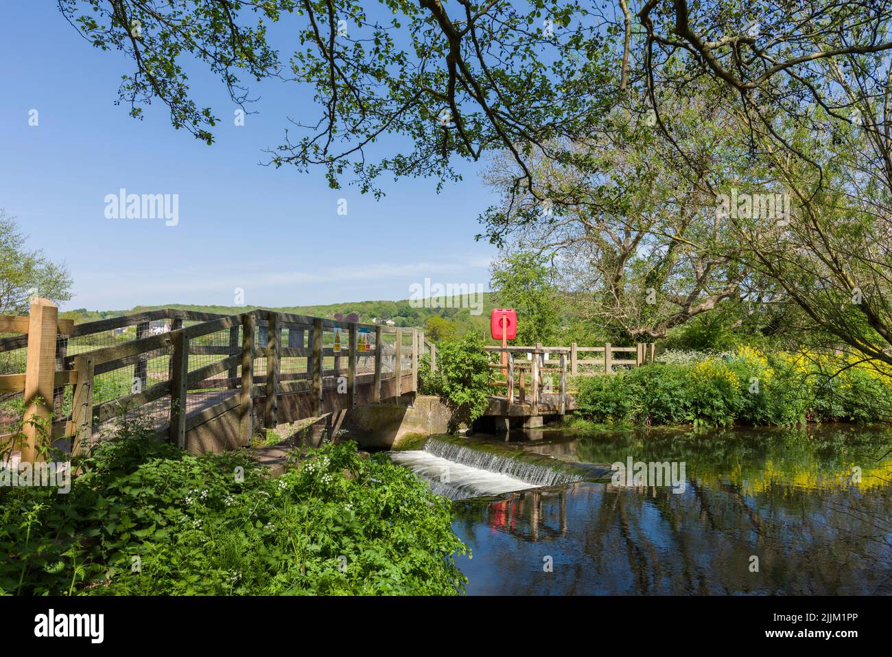 The footbridge over the weir on the River Yeo, also known as the Congresbury Yeo, at Congresbury, North Somerset, England. Stock Photo