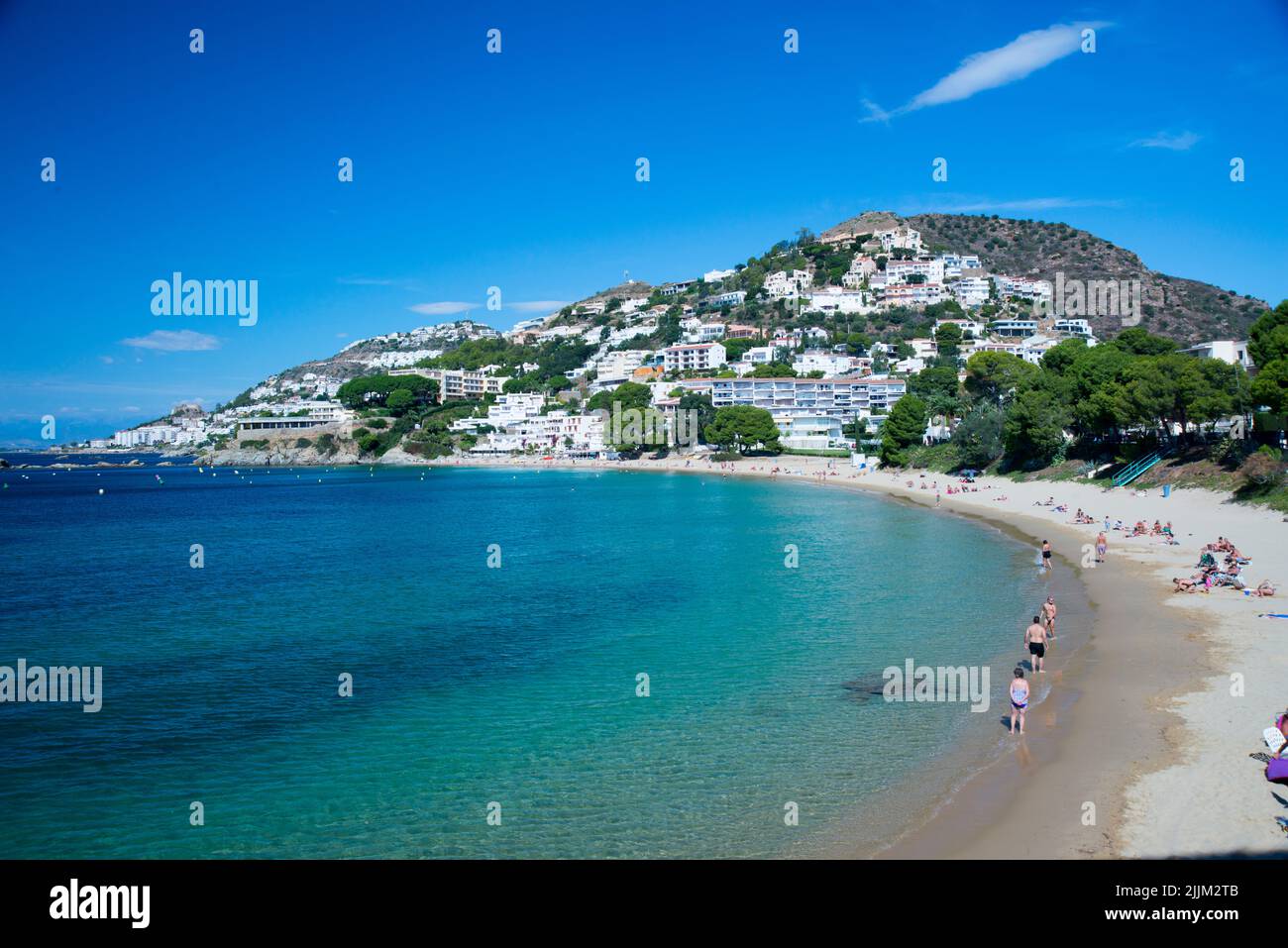 A view of a sand beach and the sea with the cityscape of Roses in the background Stock Photo