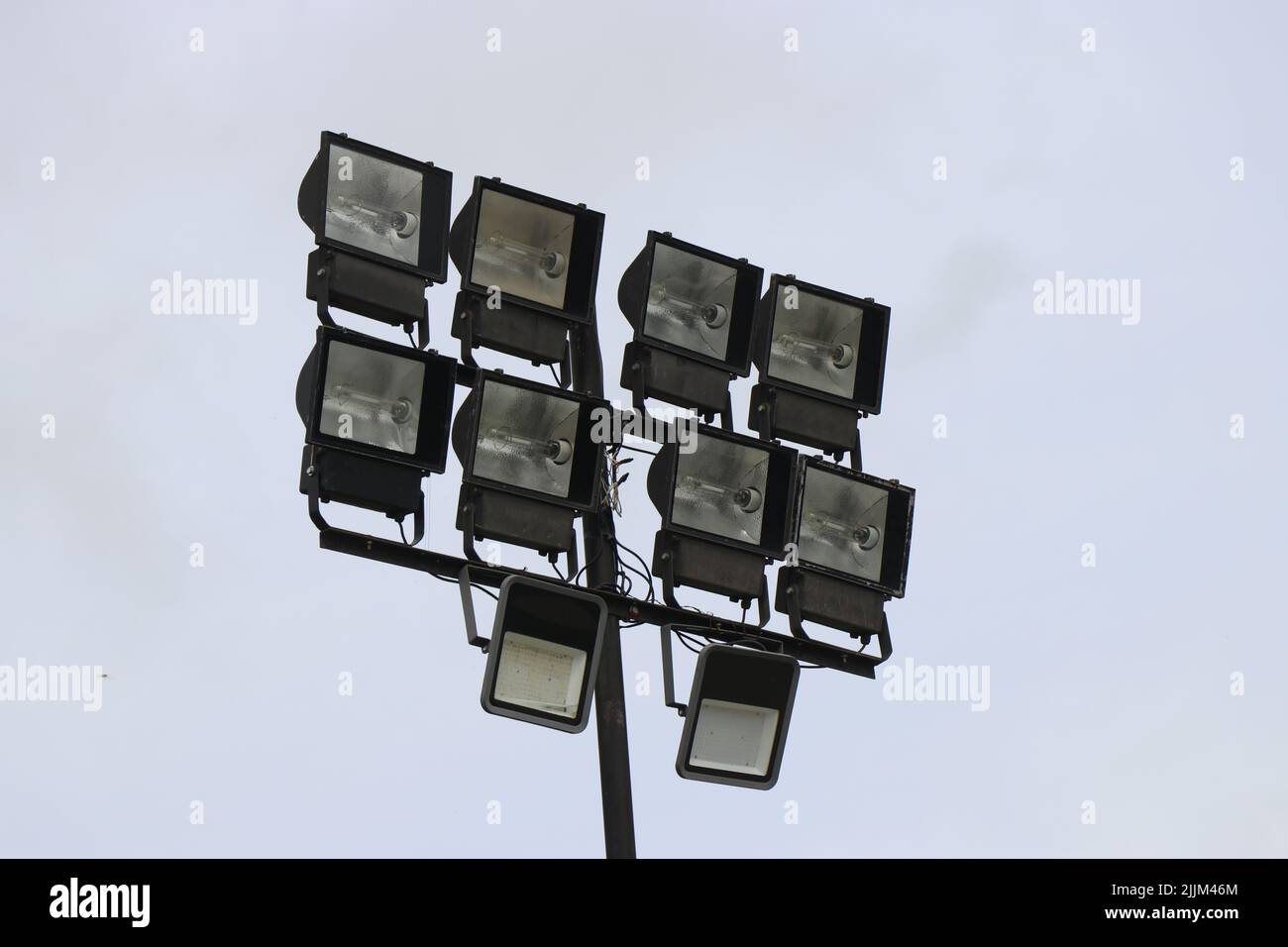 Stadium lights with many powerful halogen and LED bulb lamps attached to a tower that gives out light to the ground during the dark Stock Photo