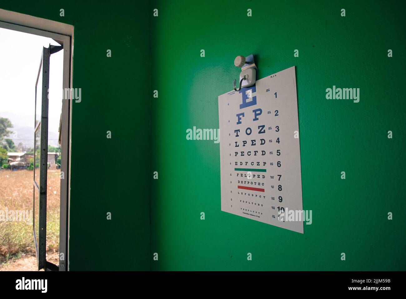 A closeup of an eye chart against a green wall Stock Photo