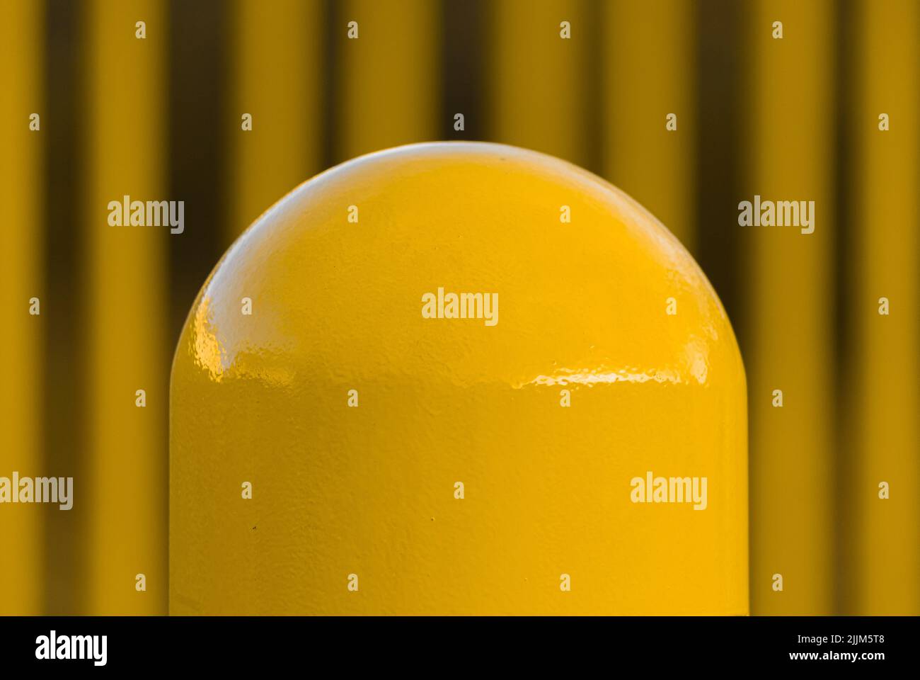 A closeup shot of a Yellow Pole on a blurry yellow fence background Stock Photo